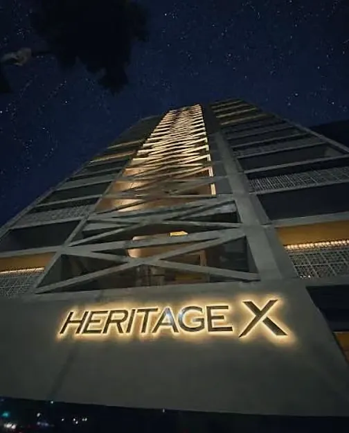 The Heritage X sign lit at night, below the illuminated X-shaped structure